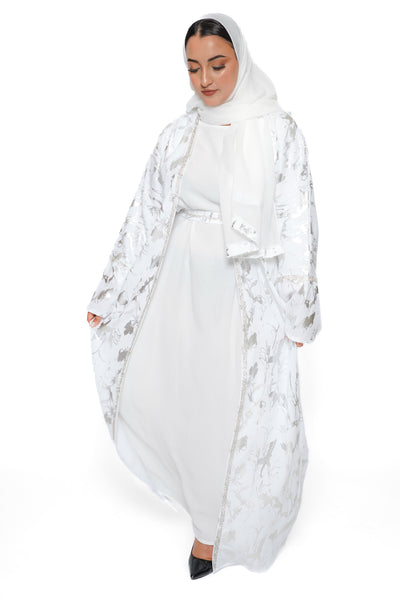 Abaya Lujayn en satin fluide beige avec broderies dorées sur les manches – vue en mouvement